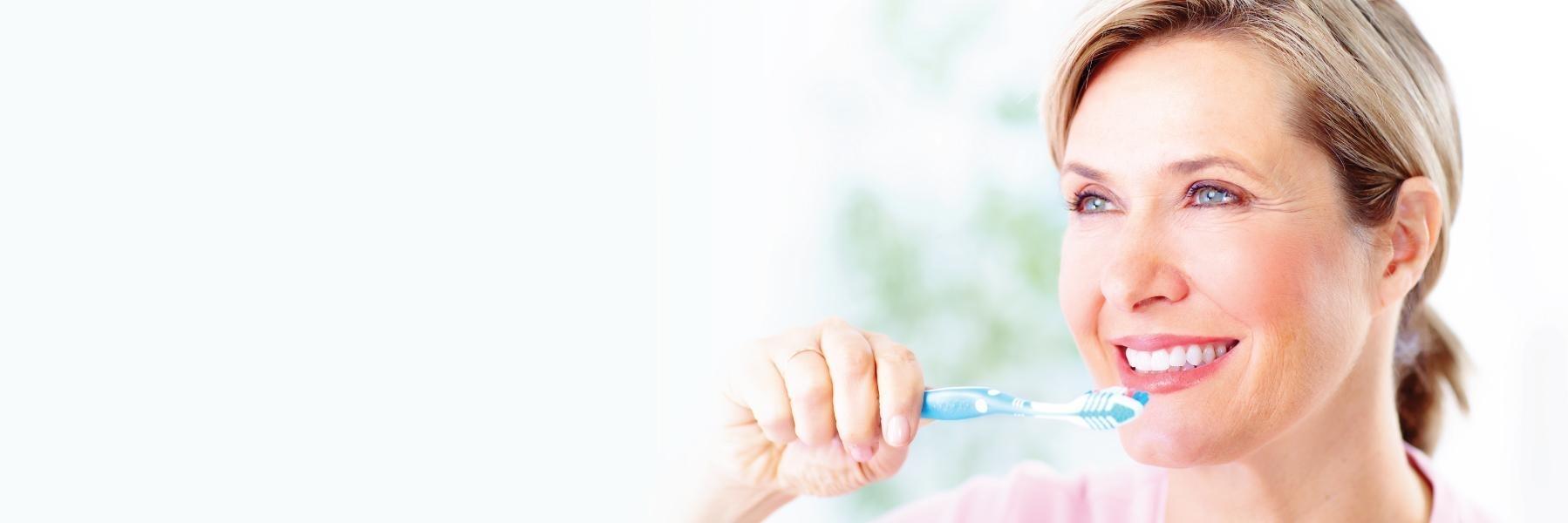 Woman brushing her teeth at dentist office in Eagan MN