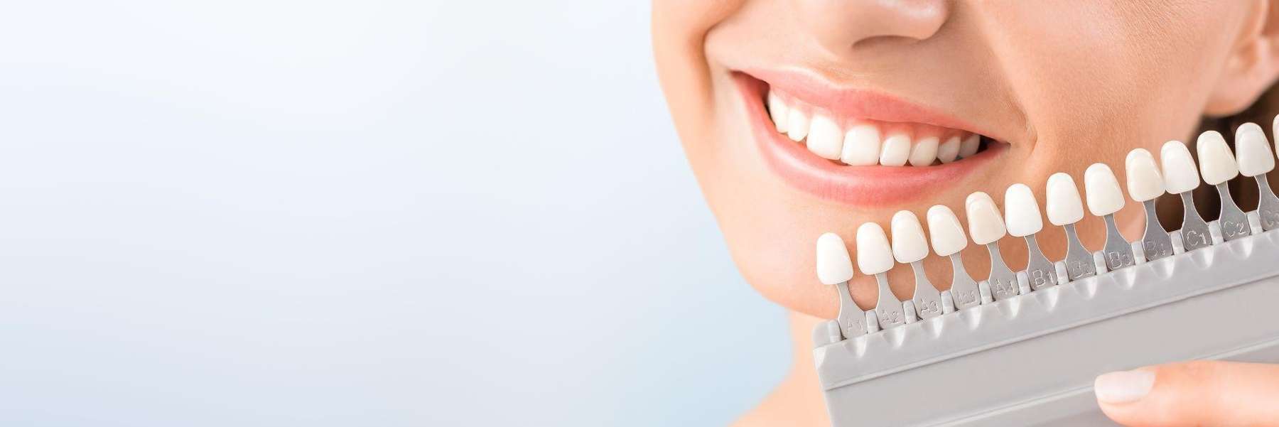 Female holding tooth shade guide with her white teeth in Eagan MN
