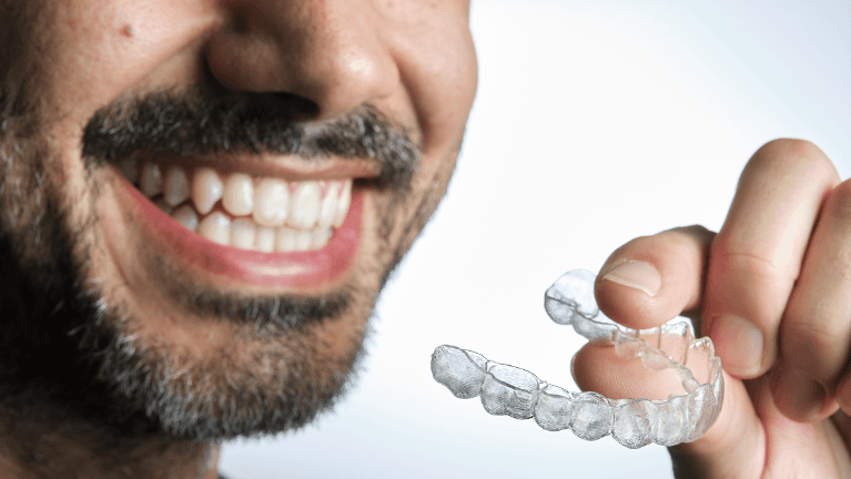 Bearded man holding a clear aligners in Eagan MN