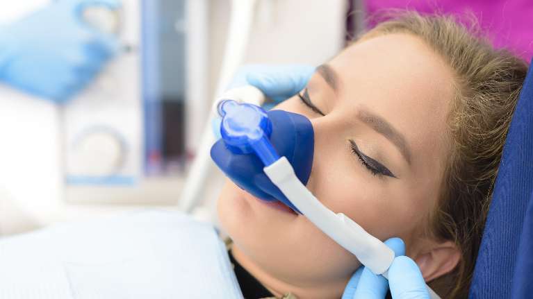 A woman sits comfortably on a dental chair