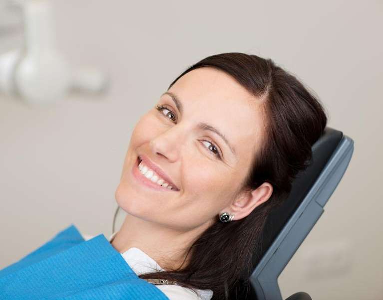 A smiling woman in a dental chair, showing a smooth dental implant recovery.