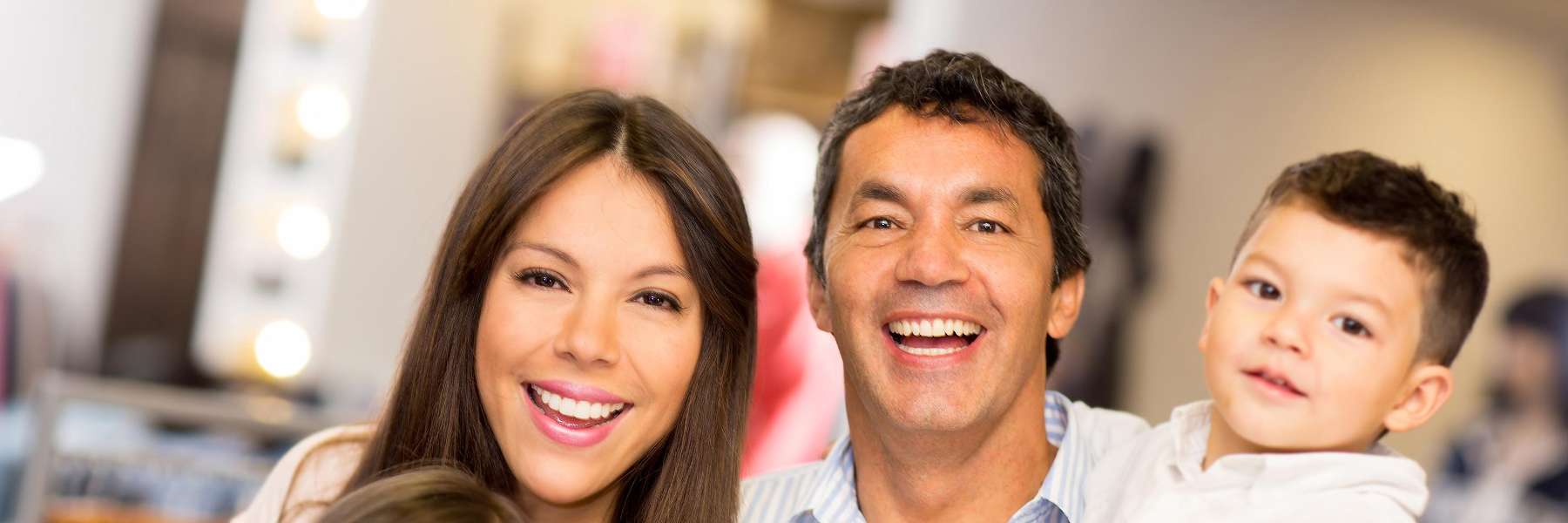 A cheerful family stands inside a brightly lit dental clinic