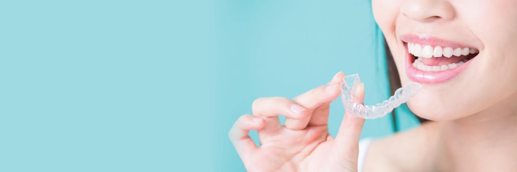 Woman holding up SureSmile clear aligners in Eagan MN
